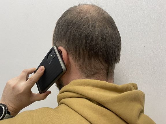 mężczyzna stojący tyłem rozmawiający przez telefon
