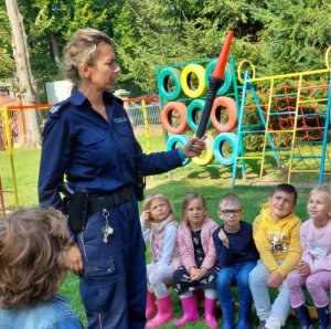 Policjantka stoi przed dziećmi z latarką do kierowania ruchem