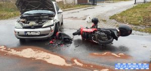 Zdjęcie przedstawia samochód osobowy i rozbity motorower w miejscu zdarzenia drogowego