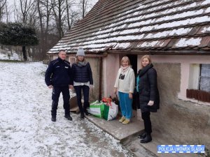 Policjant wraz z trzema kobietami stoją pod domem