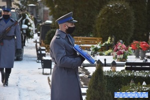 Zdjęcie przedstawia policjanta przed grobem zmarłego