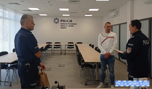 Dwóch policjantów i mężczyzna stoją w sali konferencyjnej