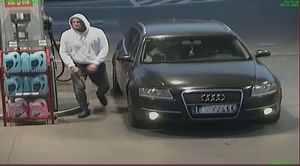 Mężczyzna w białej bluzie z kapturem przy czarnym audi