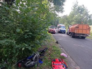 Zdjęcie miejsca wypadku. Widoczny wóz strażacki, karetka, śmieciarka i motorower