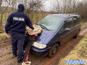 Policjant trzyma zatrzymanego na masce samochodu