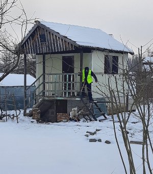 Zdjęcie przedstawia umundurowanego funkcjonariusza w odblaskowej kamizelce, który sprawdza opuszczoną altankę na działkach