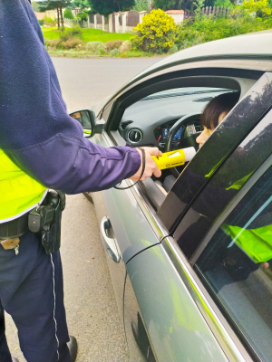 Zdjęcie przedstawia policjanta, który bada trzeźwość osoby kierującej