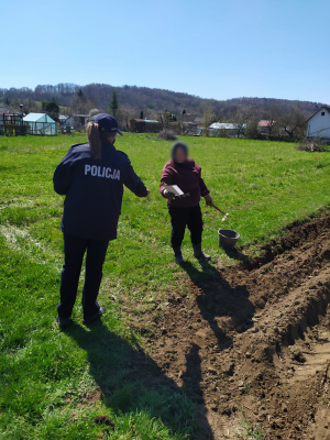 Zdjęcie przedstawia policjantkę w mundurze, która rozmawia z seniorką i przekazuje jej ulotki i odblaski