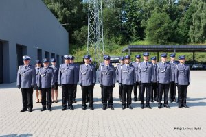Zdjęcie przedstawia 18 funkcjonariuszy na placu, którzy są ubrani w mundur wyjściowy i stoją w dwóch szeregach