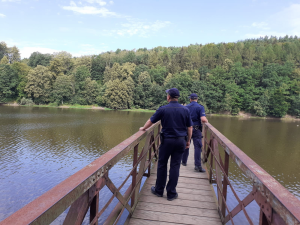 Zdjęcie przedstawia dwóch policjantów na pomoście, którzy obserwują akwen wodny